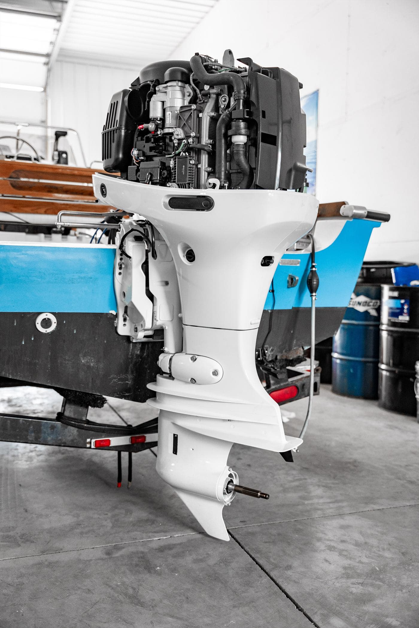 Suzuki outboard mounted on the transom of a blue center console boat in the shop