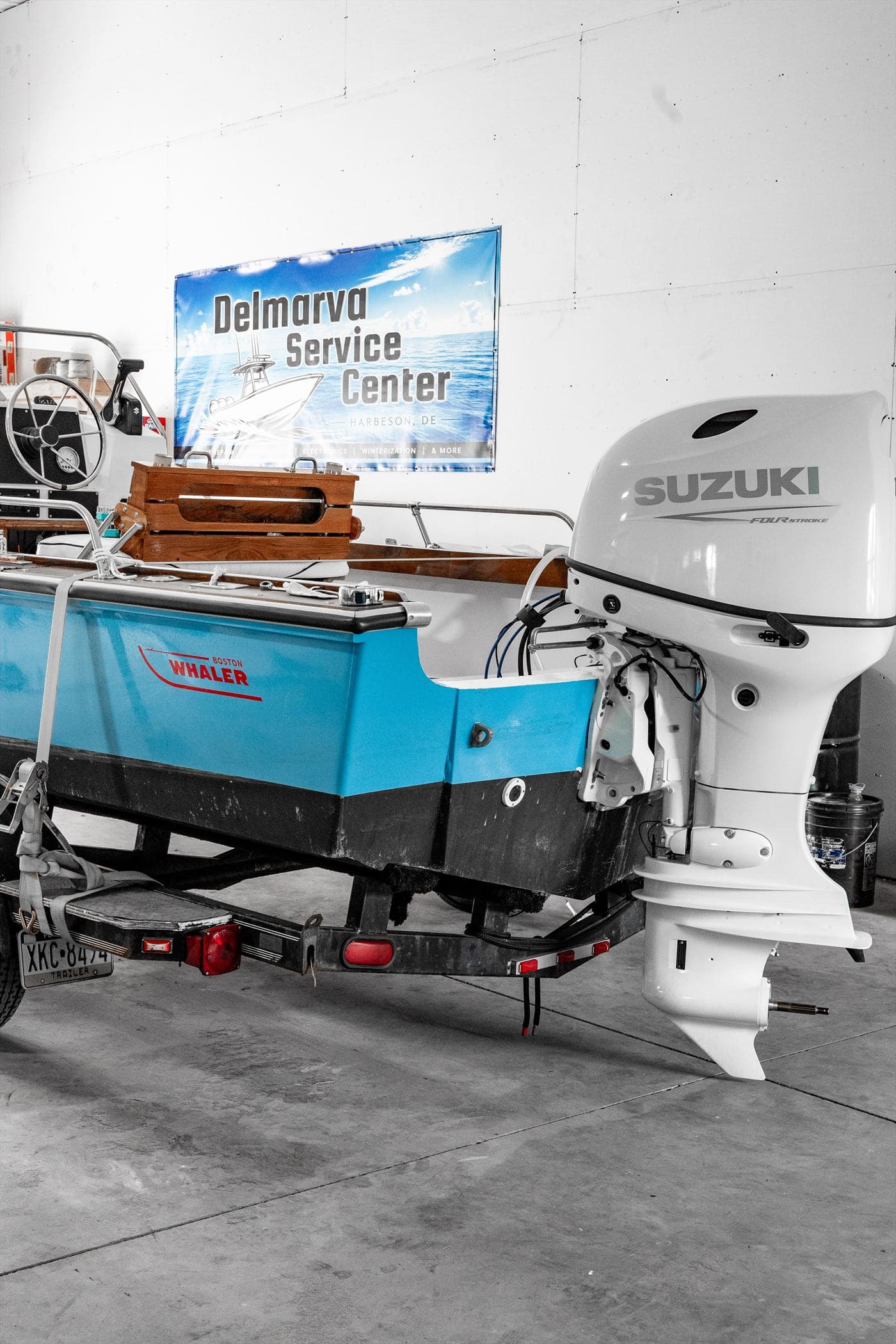 Suzuki outboard on a teal bay boat inside the Delmarva Service Center shop