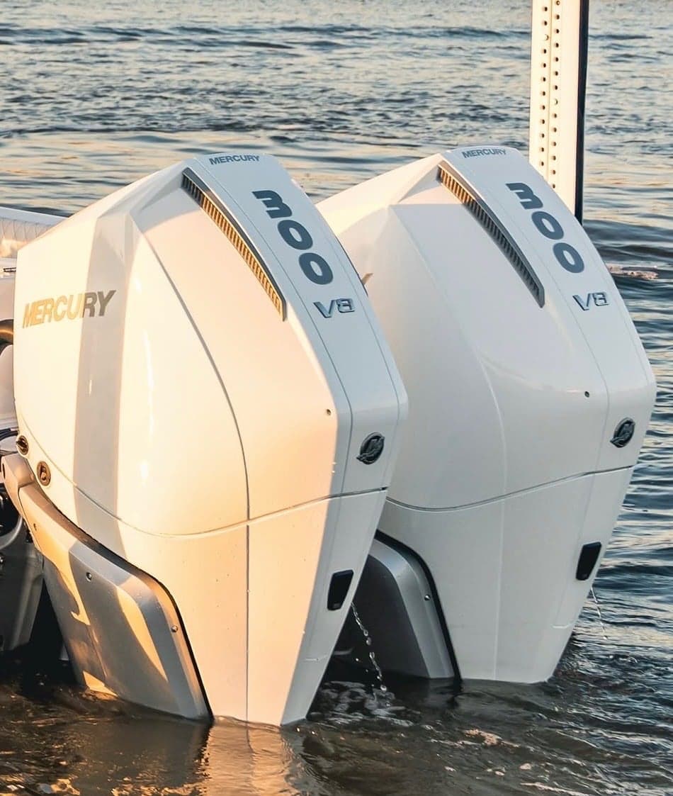 Twin white Mercury 300 V8 outboards mounted on a boat transom, sitting at the waterline in evening light