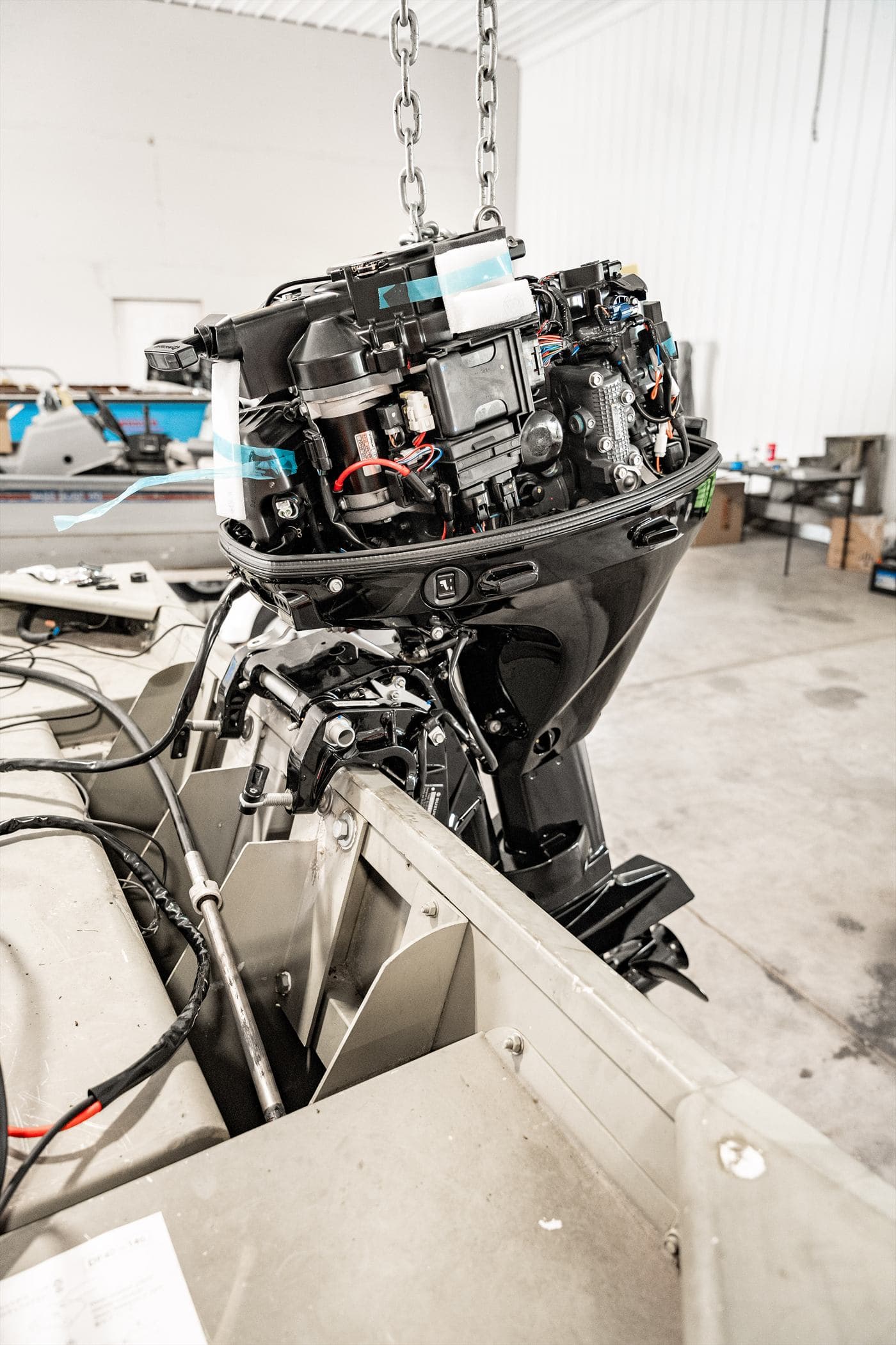 Outboard powerhead lifted on a chain hoist during a repower