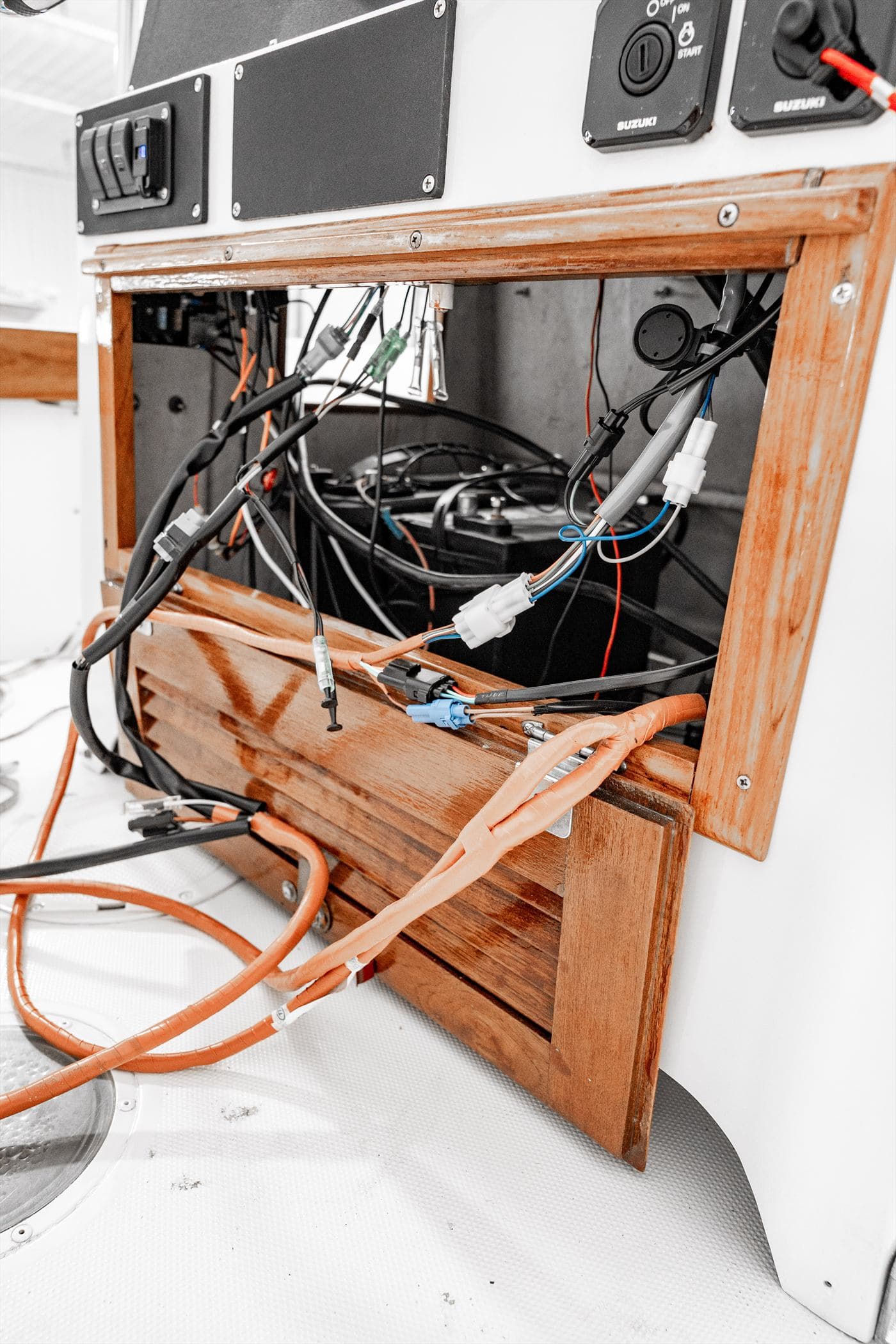 Hydraulic steering lines and wiring harnesses inside an opened boat rigging bay